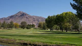 Image of "M" Mountain as seen from the NMT Golf Course. The green grass of the golf course is seen in the image foreground.